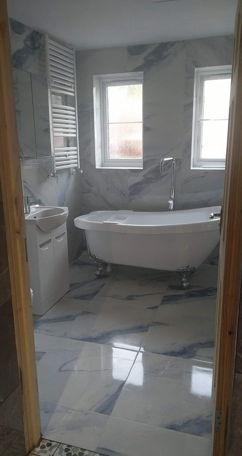 Bathroom with a freestanding bath and glossy marble-effect floor