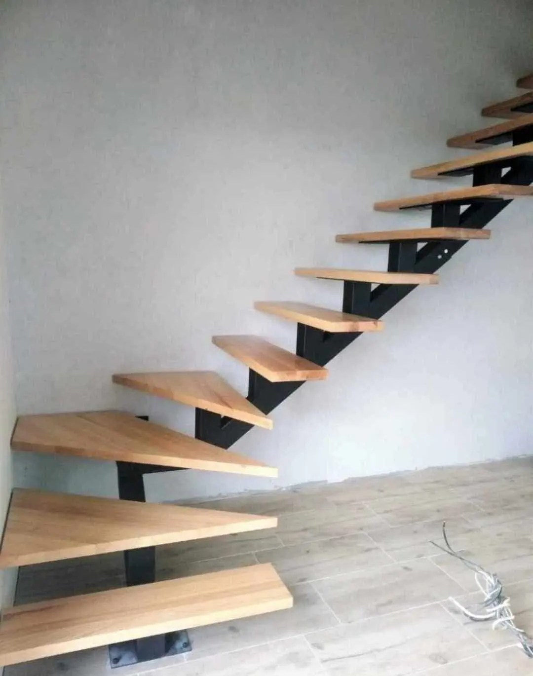 Floating oak treads on a black steel spine against a white wall