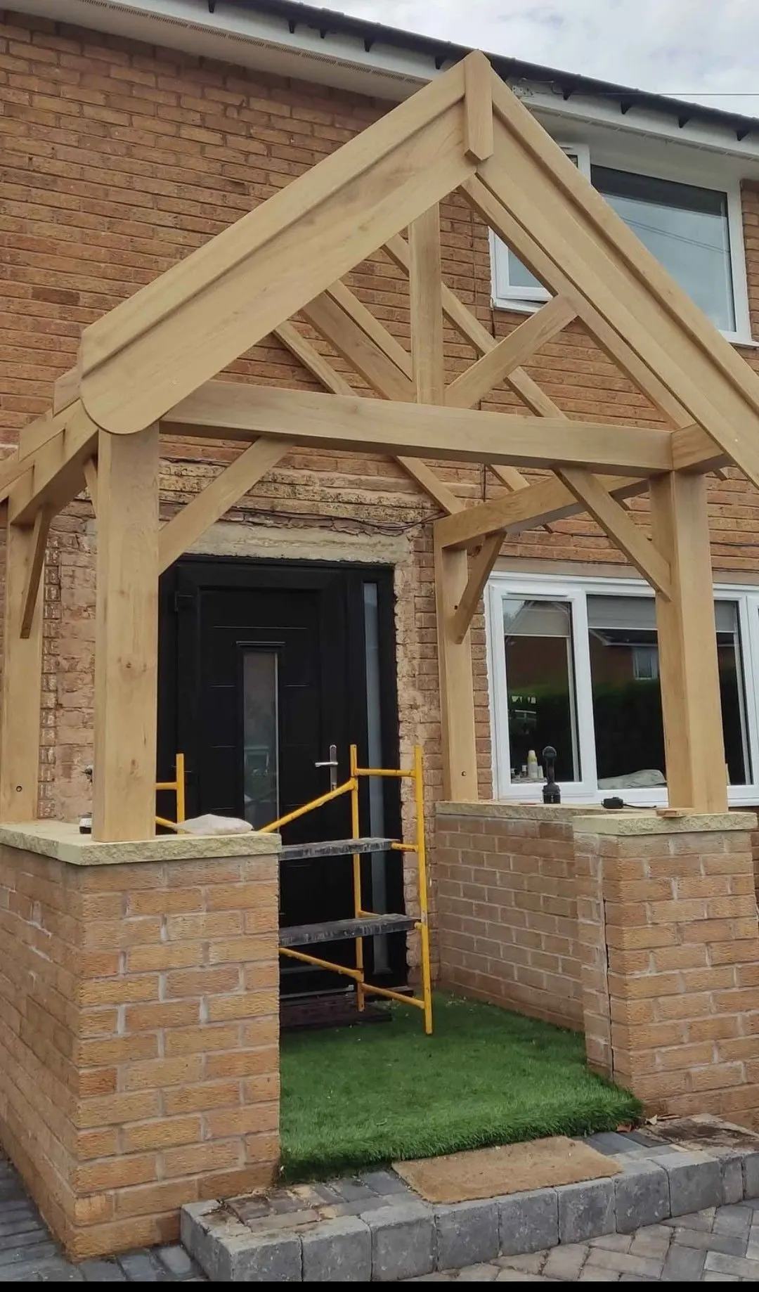 Oak-framed gabled porch with a pitched tiled roof over a brick base