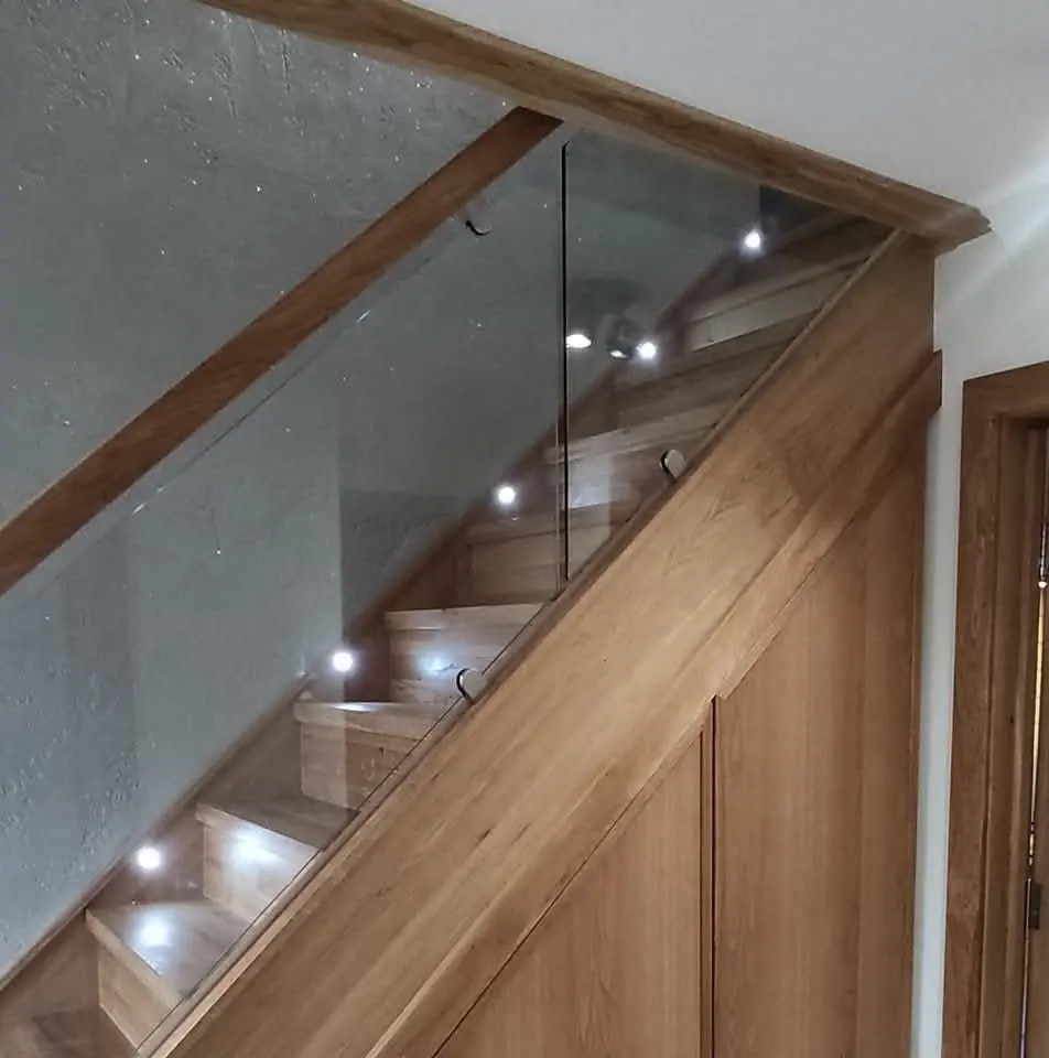Oak staircase with a glass balustrade and recessed downlights