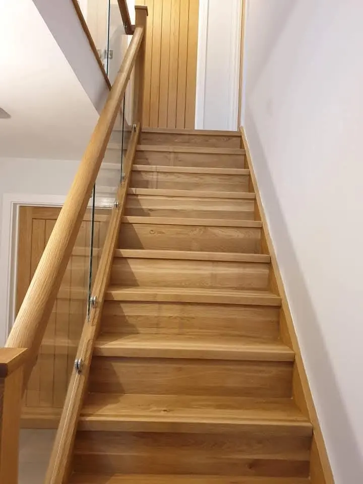 Oak staircase with a glass balustrade and a rounded oak handrail