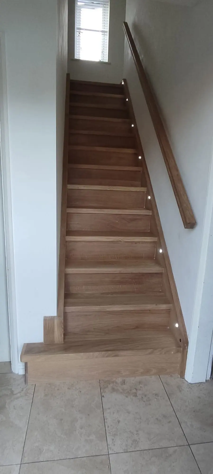 Narrow oak staircase with small step lights and a timber handrail