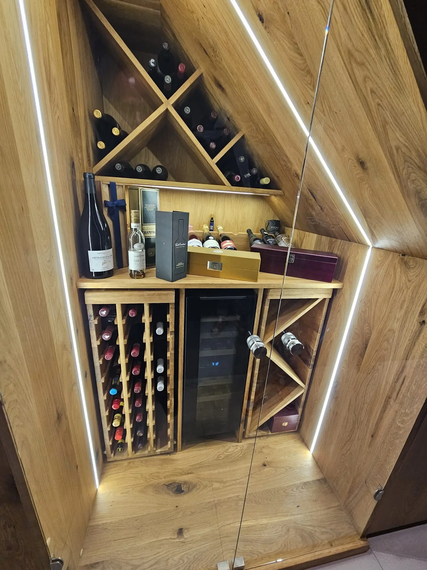 Solid oak under-stairs wine cabinet with LED strip lighting, wine racks and a glass door